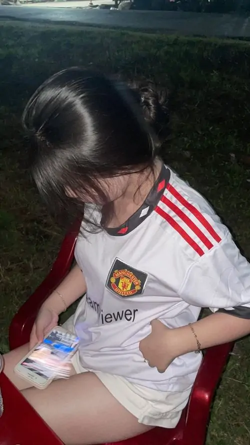 19 Cô gái mặc áo bóng đá cúi nhìn món đồ trên tay như che bớt gương mặt giữ hồn nhiên học trò