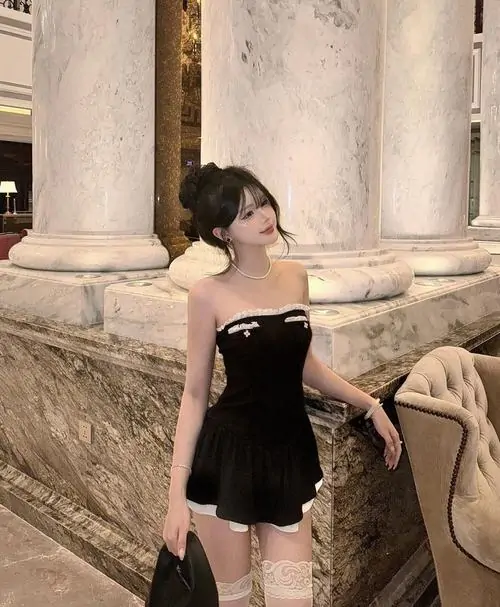 14 Trước hàng cột đá cổ điển, cô gái mặc đầm đen ngắn trễ vai tạo dáng một bên tay cầm túi, nền ảnh sang nên tổng thể trông đẹp và quyến rũ, chất vải mềm làm bộ hình có cảm giác thanh lịch hơn hẳn