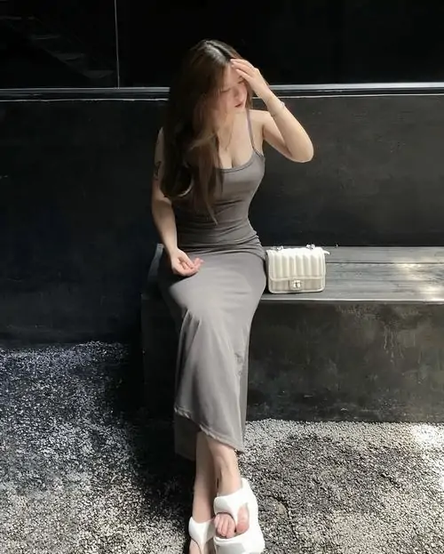 20 Cô gái diện đầm xám dáng dài đứng bên mảng tường tối ngoài trời, tay che nắng và tóc nâu buông thẳng khiến ảnh có nét trầm, phần thân váy ôm nhẹ nên giữ được sự thanh lịch và hợp kiểu ngắm lâu không chán