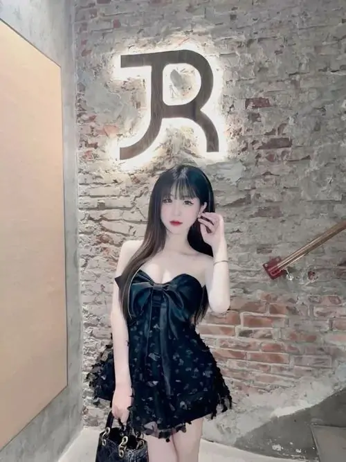 22 Dưới ánh đèn biển hiệu, cô gái mặc váy ngắn tối màu đứng tựa tường đá, tóc dài và biểu cảm thả lỏng làm khung hình có chút nổi loạn, lên rõ lớp trang điểm nhẹ nên tổng thể vừa teen vừa khá lôi cuốn