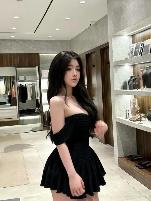 24 Trong sảnh sáng màu, cô gái mặc đầm đen ngắn bước nhẹ qua kệ trưng bày, mái tóc dài ép thẳng và ánh mắt nghiêng làm khung hình thêm cuốn, bức này hợp kiểu thần thái lạnh mà cuốn nhìn càng lâu càng thấy mê