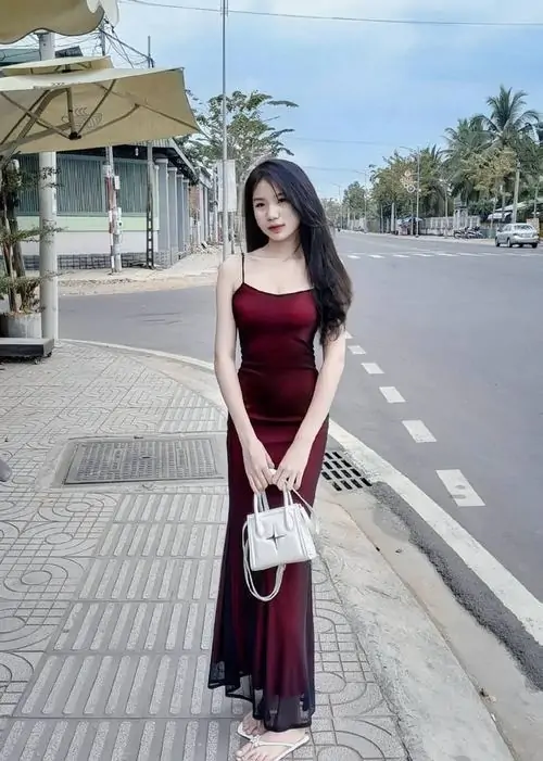 7 Hình gái xinh mặc váy dài đỏ rượu đi trên vỉa hè rộng, tay xách túi trắng nhỏ và dáng bước tự nhiên khiến khung hình có nét dịu, vừa đẹp vừa thanh lịch, đúng kiểu ảnh gái đẹp mặc váy ôm hợp cảnh phố chiều yên ắng