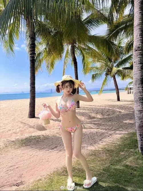 12 Ảnh hot girl mặc áo tắm màu kem đứng dưới hàng dừa đội nón rộng vành cười tươi trên bãi cát gió