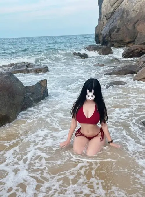 34 Cô nàng quỳ trên bờ cát với bộ đỏ nổi bật phía sau là biển xanh nắng vàng và bọt sóng trắng