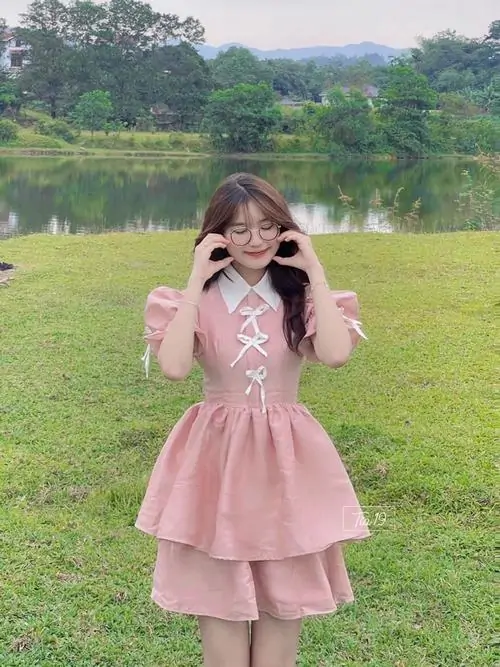 10 Ngoài bãi cỏ, ảnh thiếu nữ mặc váy hồng ngắn đưa tay lên má, dáng vẻ pinky khiến tổng thể nhìn hiền