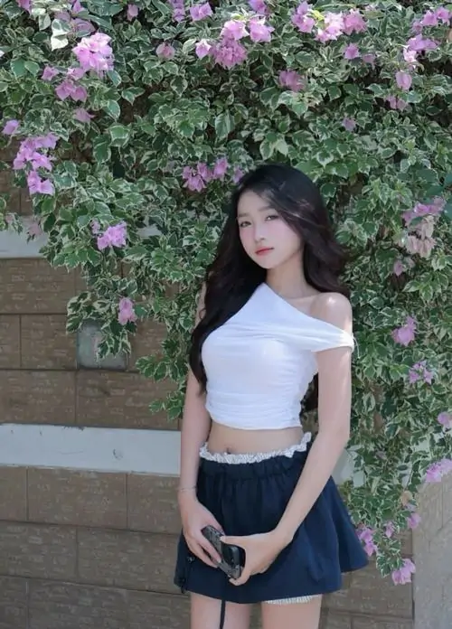 19 Bức hình gái xinh với áo trắng và chân váy xanh đứng trước bức tường hoa tím, bàn tay đặt trước bụng và dáng nhìn sang bên khiến khung hình mềm mắt, nữ tính mà vẫn có điểm nhấn cuốn hút