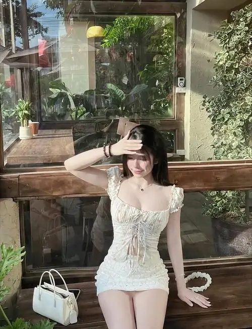 20 Bên hiên quán phủ cây xanh, cô gái diện váy len sáng màu ôm dáng ngồi nghiêng trên ghế, một tay chống nhẹ tạo cảm giác thư thái, ảnh cô gái mặc đầm này trông đẹp, gợi cảm và rất đời thường