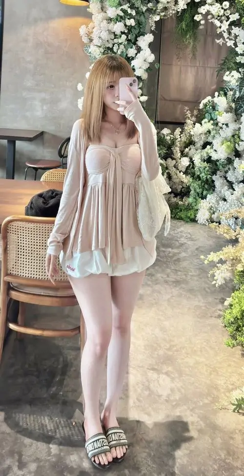 6 Cô gái mặc đầm bèo màu kem đứng dưới mái hiên đầy hoa, vóc dáng mảnh và bước chân khép nhẹ khiến khung hình toát ra cảm giác bay bổng, làn da sáng làm tổng thể thêm sexy mà vẫn tinh khôi