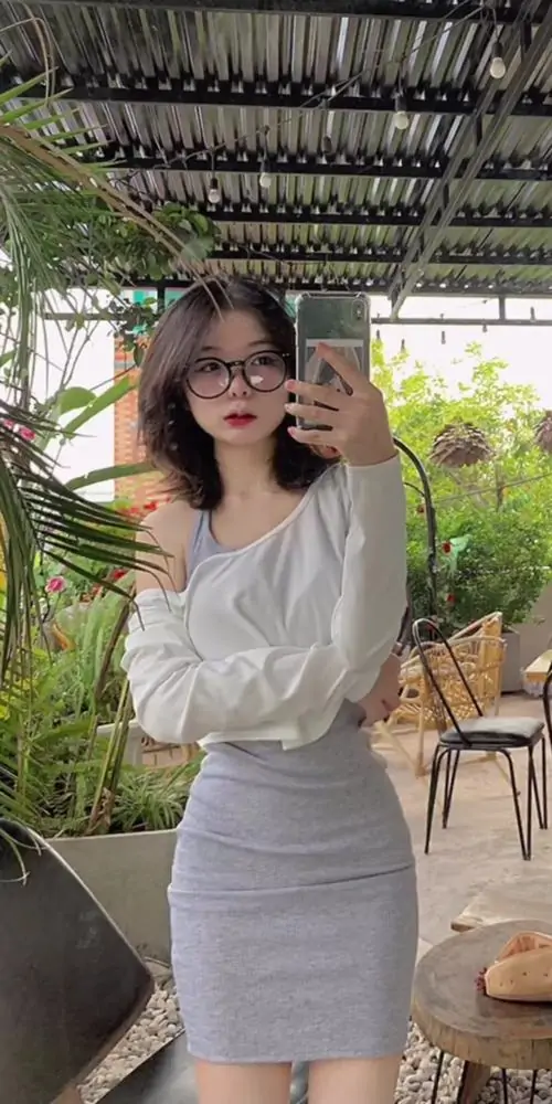 8 Khung hình bắt trọn cô gái áo trắng ôm sát cùng chân váy xám trong quán cà phê, cặp kính đen và bờ vai trần tạo điểm nhấn sexy rõ nét, đồng thời giữ được nét dễ thương rất hợp mắt