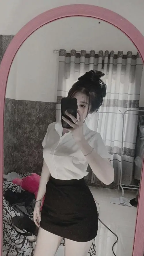 35 Đứng trước gương ảnh cô gái phối sơ mi trắng với váy ngắn tối màu cho dáng nhìn gọn gàng và rất có điểm nhấn