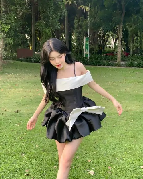 14 Thiếu nữ dễ thương xoay nhẹ trên thảm cỏ trong váy chữ A đen khiến đôi chân trông dài và khung hình thêm trẻ trung