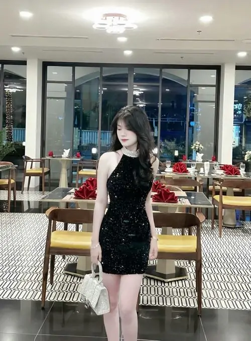 7 Mỹ nhân đứng giữa sảnh sáng với váy ngắn đen ôm nhẹ để lộ đôi chân thon và vẻ ngoài sang chảnh