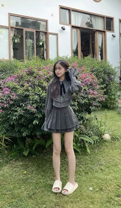 1 Ảnh cô gái diện váy chữ A xếp nếp đi cùng giày thể thao trắng giữa phố chiều mang vẻ gọn gàng và cực kỳ tôn dáng