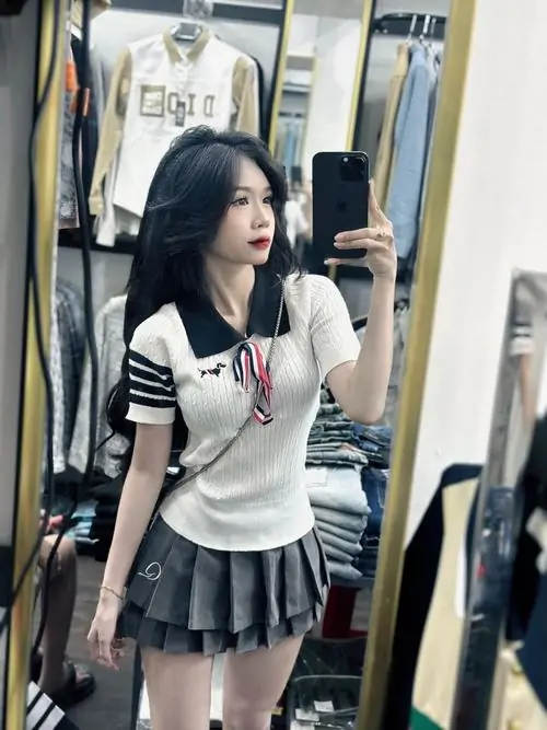 32 Ảnh gái xinh mặc váy tennis ngắn đứng nghiêng bên lan can tóc buông nhẹ làm nổi bật vòng eo và dáng vẻ trẻ trung