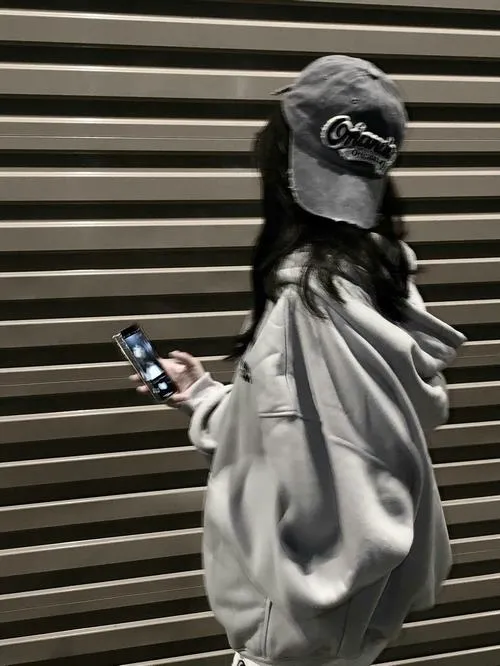 30 Ảnh gái chất chơi giấu diện mặc hoodie bóng đứng nghiêng trước cửa cuốn che nửa mặt bằng mũ tối màu