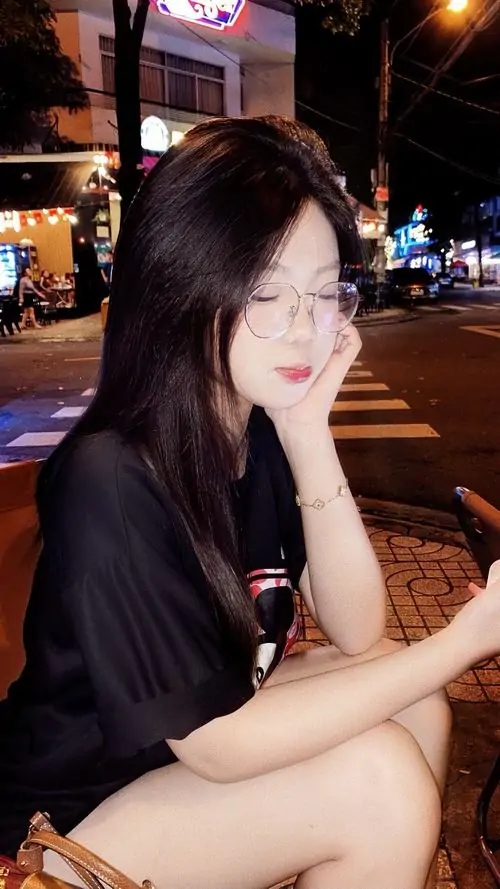 9 Góc chụp hot girl về đêm với mái tóc buông dài và làn da sáng nổi bật dưới ánh đèn phố, cô gái mặc áo tối màu ôm tay trước ngực, ánh nhìn nghiêng tạo sắc lạnh vừa đủ khiến tổng thể càng thêm lôi cuốn