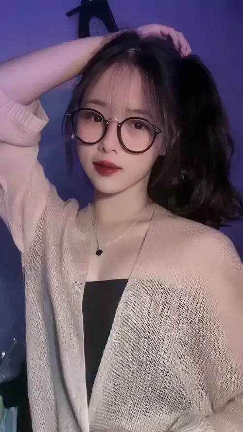 14 Cô gái đeo kính tròn đứng trong ánh sáng tím dịu, tay vòng lên đầu và khoác áo len hờ bên vai, bờ môi nhẹ nhàng cùng biểu cảm mềm khiến bức ảnh vừa nữ tính vừa có chất riêng rất dễ làm người xem lưu lại