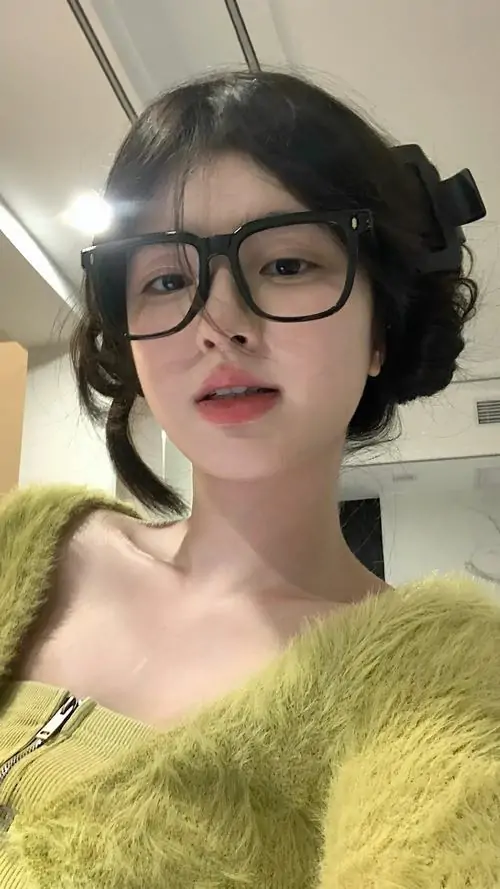17 Ảnh hot girl cắt cận gương mặt với tóc ngắn uốn nhẹ và áo len xanh non trễ vai, kính đen bản to làm sống mũi thêm nổi bật, biểu cảm thản nhiên tạo cảm giác hiện đại, trẻ trung và đầy sinh khí