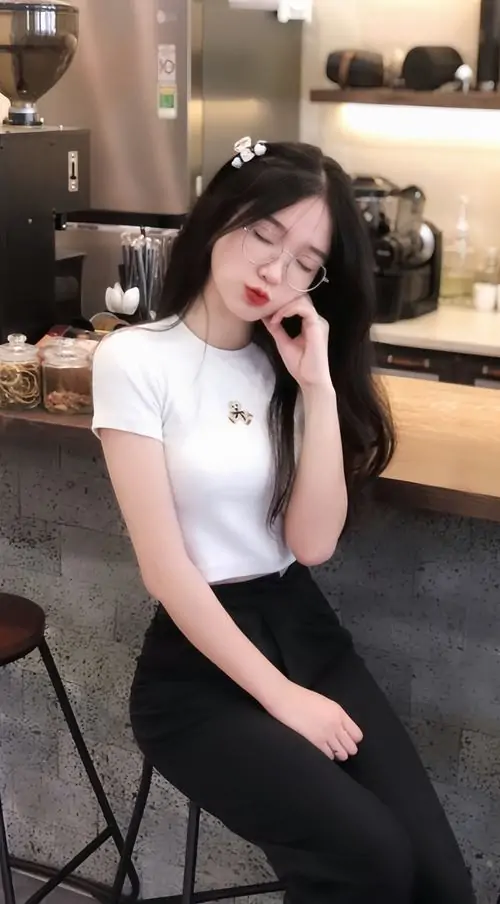 27 Góc chụp cô nàng trong quán với áo trắng ôm gọn và quần tối màu, cô gái hơi nghiêng đầu tựa tay lên má, ánh mắt mơ màng giúp ảnh gái xinh ngầu đeo kính giữ được vẻ mềm mại mà vẫn nổi bật