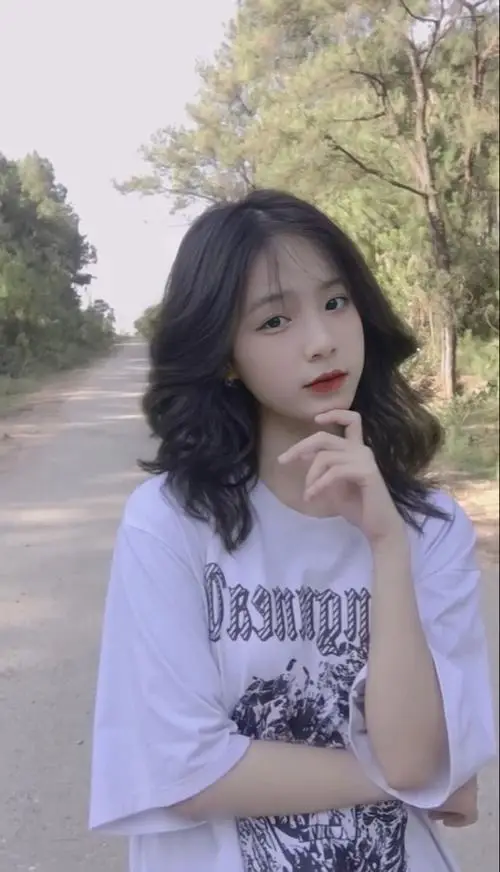 21 Mỹ nhân tóc xoăn ngắn mặc áo tím đứng giữa lối cây xanh biểu cảm trầm khiến khung hình thêm thanh thoát