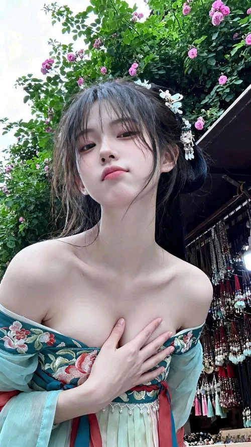 1 Gái đẹp Nhật Bản diện váy ôm xám tay chạm tóc, ngực nổi bật cùng thần thái cuốn hút kiểu idol giữa nền cây xanh dịu mắt.