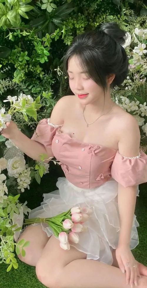7 Trong khu vườn xanh mát, cô gái mặc váy hồng trễ vai ôm bó hoa nhỏ, ngồi nghiêng nhẹ và cười e ấp, khiến bộ ảnh người đẹp nổi bật toàn cầu mang vẻ mềm mại, tự nhiên và rất hợp khung hình mùa hè