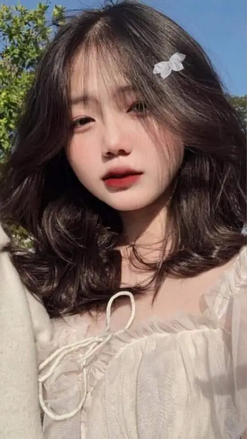 37 Mỹ nhân dựa tường trắng với đèn mềm hắt nhẹ lên má làm khung hình sáng đều và rất dễ gây thiện cảm