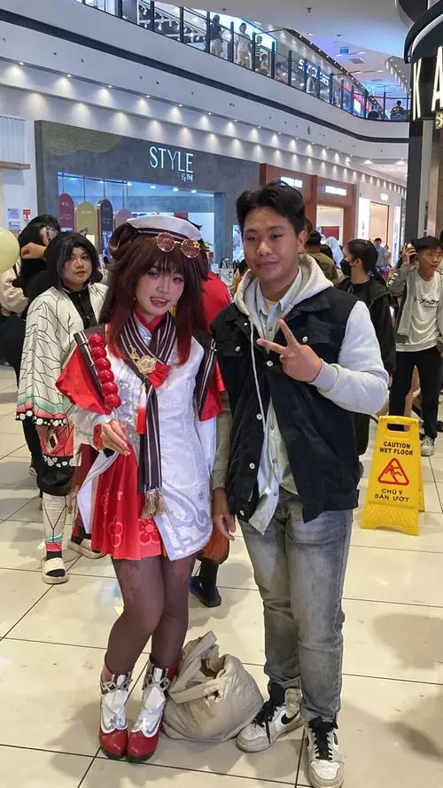 1 Ảnh gái đẹp cosplay Việt chụp trong trung tâm thương mại với váy đỏ trắng nổi bật và dáng đứng tự nhiên bên lối đi đông người