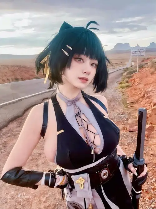 24 Gái đẹp cosplay Việt với tóc xanh đen ngắn áo hở vai và găng tay đen đứng giữa khung cảnh núi đá đầy bụi gió