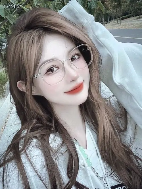 7 Hình nữ cận mặt với lớp áo trùm đầu sáng màu, tóc nâu xoã mềm và góc nghiêng nhẹ khiến gương mặt trong trẻo hơn, nhưng ánh mắt trực diện vẫn giữ được chất cô gái bí ẩn giữa nền ngoài trời mờ nắng