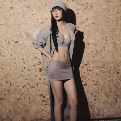 12 Khung hình đường phố cho thấy Juky San diện blazer xám cùng chân váy ngắn, đứng nghiêng trước bức tường sần màu cát, tạo nên cảm giác cá tính mà vẫn ngọt, như một phiên bản khác của thần thái trong trẻo thường thấy