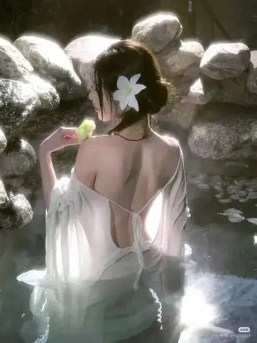 16 Người mẫu ngâm mình trong mặt nước lấp lánh, hoa trắng lớn bao quanh phần vai ngực, ảnh khỏa thân nghệ thuật thiên về vẻ đẹp thuần khiết, dùng ánh phản chiếu để giữ khung hình mềm, mát và có độ mơ nhẹ