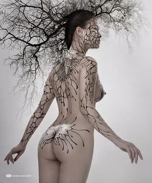 20 Ảnh lưng trần với họa tiết cành cây phủ dọc thân sau, người mẫu đứng nghiêng trên nền sáng trắng, ảnh cơ thể nghệ thuật nhấn vào cột sống và cấu trúc xương, tạo ấn tượng mộc mạc mà vẫn rất hiện đại