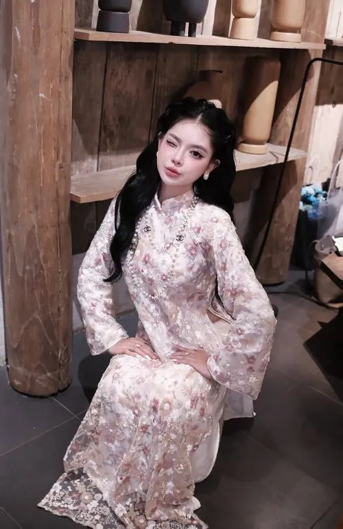 11 Cô gái mặc váy hoa ngồi giữa không gian gỗ tối mang nét dịu dàng cổ điển như một khung hình lặng của tuổi trẻ