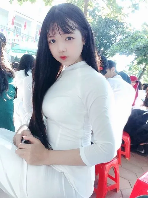 24 Nữ sinh áo dài trắng nghiêng người giữa khoảng sân có ghế đỏ tạo cảm giác thanh thoát và dịu dàng trong từng đường nét