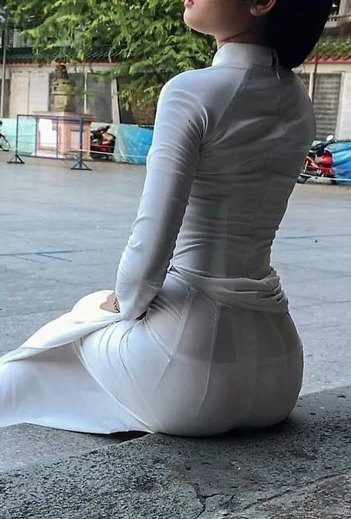 4 Nữ sinh trong áo dài trắng ngồi nghiêng giữa khoảng sân rộng tà áo ôm dáng nhẹ tạo vẻ đẹp yên tĩnh và cuốn mắt