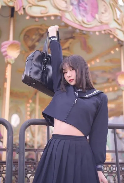 37 Nữ sinh mặc áo tối váy xếp ly giơ tay trước nền đèn rực tạo cảm giác vui mắt và có chút nghịch ngợm đáng yêu