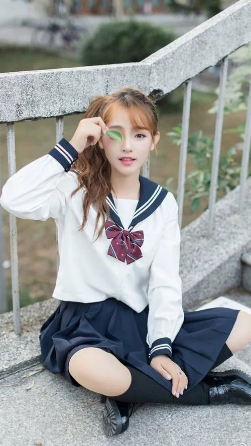 16 Gái đẹp ngồi bậc thềm với áo thủy thủ và tóc buộc hai bên biểu cảm tinh nghịch nhưng vẫn tự nhiên