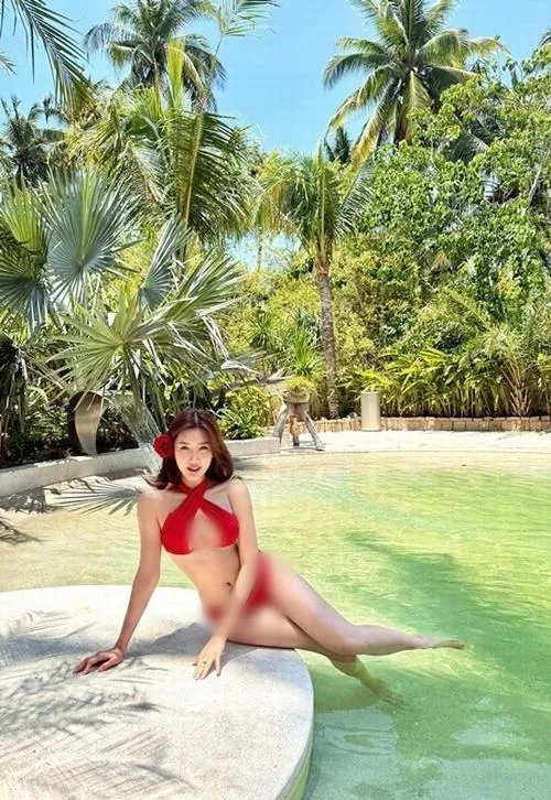 1 Thúy Ngân ngồi trên cát, tóc buông nhẹ, da bắt sáng, đôi đùi thon dài tạo cảm giác quyến rũ