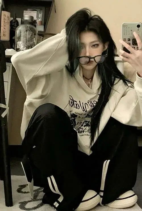 25 Ảnh phong cách tomboy với cô gái tomboy diện áo hoodie rộng, đứng tựa tường nhìn xa, toát lên vẻ mạnh mẽ rất tự nhiên