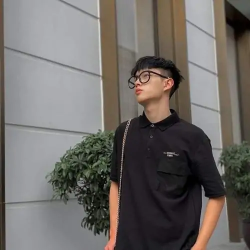 9 Ảnh cậu bạn 2k12 đứng ngoài hiên với áo đen và kính tròn, dáng ngước lên trời tạo cảm giác đeo kính thư sinh nhưng vẫn năng động, bối cảnh tường sáng gợi phong cách đời thường khá đẹp và tự nhiên