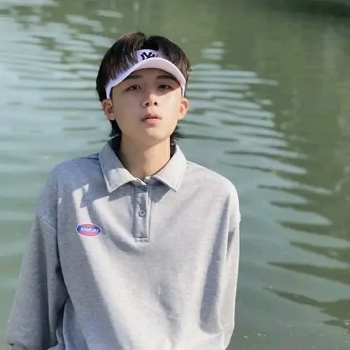 19 Hình nam sinh 2k12 đứng ngoài trời gần mặt nước trong áo xám và mũ lưỡi trai, bố cục thoáng khiến ảnh nhìn mát mắt, thần thái bình tĩnh hợp kiểu hot boy nhí gọn gàng với outfit đơn giản