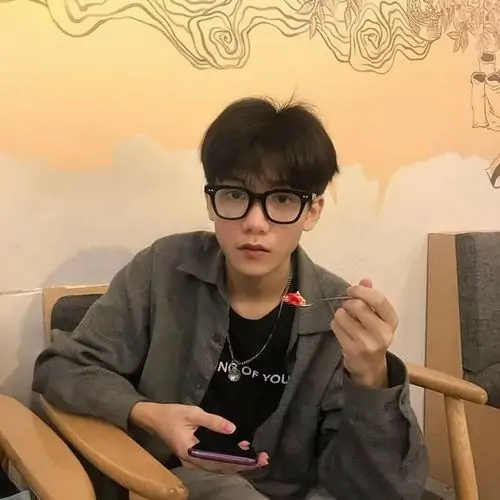 31 Ảnh chàng trai k12 đứng trước bức tường sáng trong áo đen và kính, tư thế ngửa đầu tạo cảm giác đeo kính vừa thư sinh vừa nghịch, bức hình lên màu thoáng, hợp phong cách đời thường của trai đẹp lớp 8