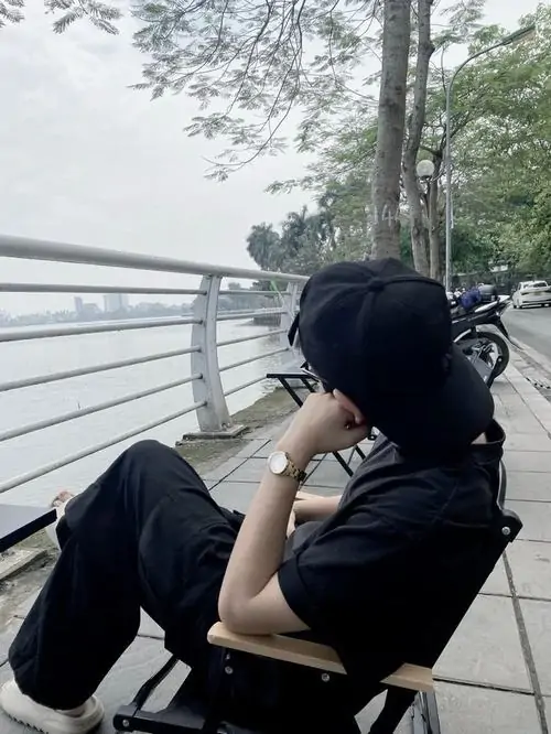 15 Hình soái ca ngồi cạnh lan can ven nước, đội nón tối kéo sụp xuống và dùng tay ôm đầu gối che thêm gương mặt, góc nghiêng khép kín tạo vẻ bí ẩn, đúng chất ảnh trai ngầu giấu mặt rất riêng