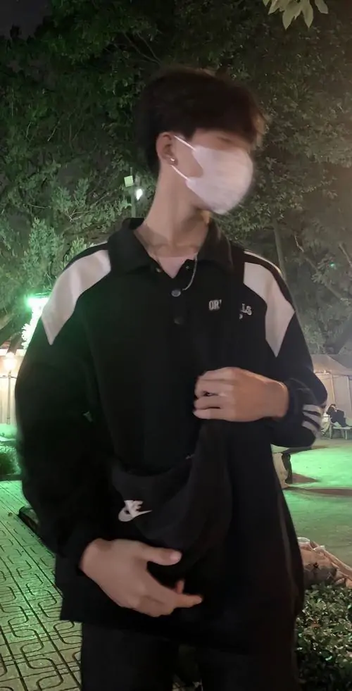 17 Ảnh mỹ nam diện áo đen có logo, đeo khẩu trang trắng và hơi nghiêng đầu ra phía sáng, phần mắt nhìn lệch tạo điểm hút, kiểu ảnh này vừa đẹp vừa cá tính, gợi rõ vẻ lạnh lùng của ảnh selfie nam lạnh lùng