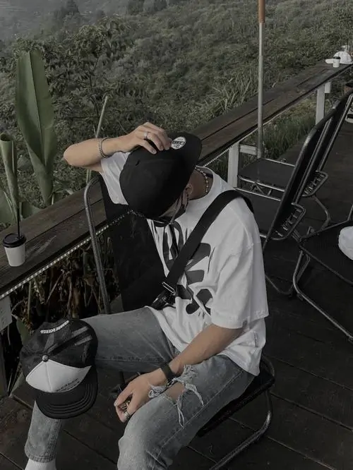 19 Hình anh chàng ngồi ở bậc thang ngoài trời, đội nón và đeo khẩu trang sáng màu che gần kín mặt, đầu cúi thấp về chiếc mũ bảo hiểm bên chân, tổng thể gọn ghẽ, đẹp và rất hợp gu tối giản