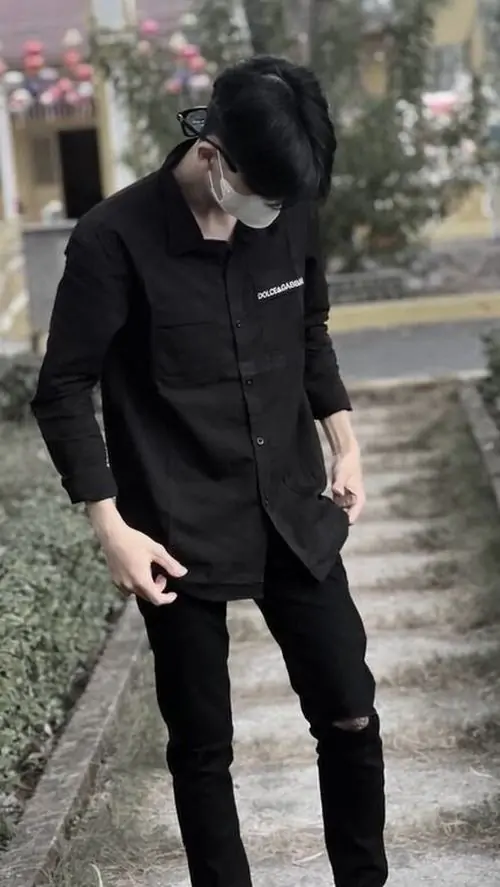 29 Ảnh chàng mặc nguyên cây đen đứng ngoài hiên, cúi hẳn đầu để tóc đổ xuống che mặt, hai tay thả dọc thân người làm dáng càng gọn, tổng thể hấp dẫn và đúng gu ảnh nam lạnh trầm ít phô bày
