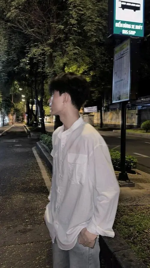 3 Hình trai áo sơ mi trắng đứng dưới đèn đường, xoay nghiêng hẳn sang bên để chỉ lộ sống mũi và đường cằm, khung hình tối giản mà đẹp mắt, hợp kiểu ảnh trai đẹp bí ẩn với bố cục gọn và mood lặng