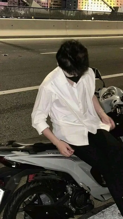 7 Hình nam mặc sơ mi trắng ngồi trên yên xe ngoài đường, cúi sâu để tóc đen phủ trọn gương mặt, phần cổ và vai thả lỏng khiến bức hình có vẻ đẹp trầm, hợp ảnh con trai giấu mặt chất