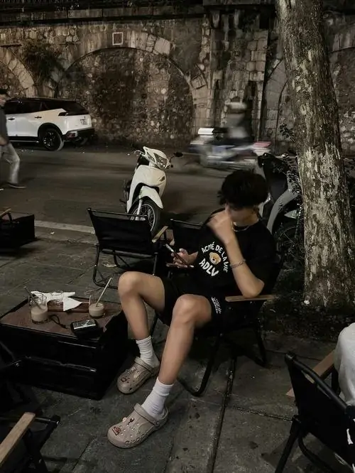 8 Giữa gốc cây lớn, cậu trai áo đen ngồi thấp và chống tay lên đầu gối, mặt quay hẳn sang bên tối nên gần như giấu kín, khung cảnh đêm làm tổng thể sexy, cuốn hút và có chút xa cách